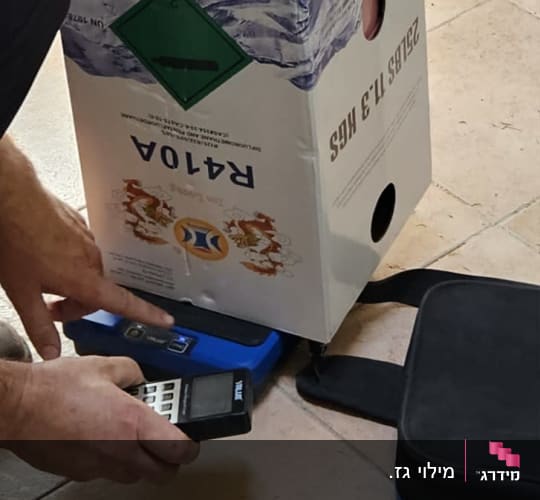 אדם מחזיק מכשיר מדידה ליד מיכל גז למזגן
